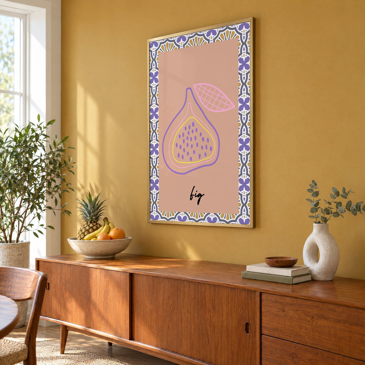 fig pastel outline purple tile print in a brass frame on a mustard wall above a teak sideboard with a fruit bowl, seen at an angle