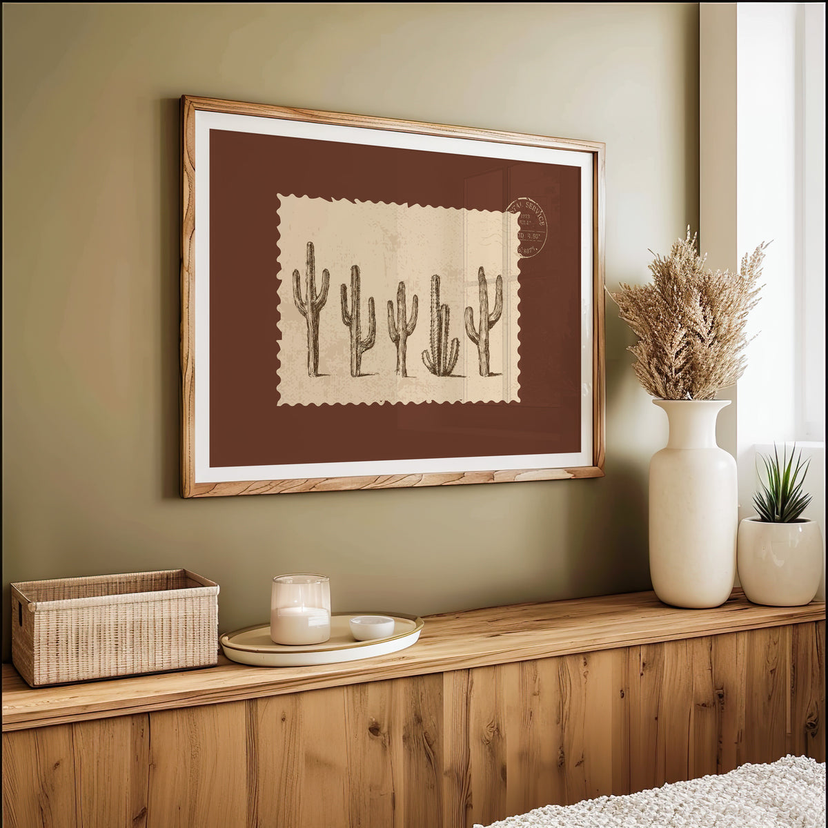 Five cacti print in an oak frame on an olive green wall above pampas grass