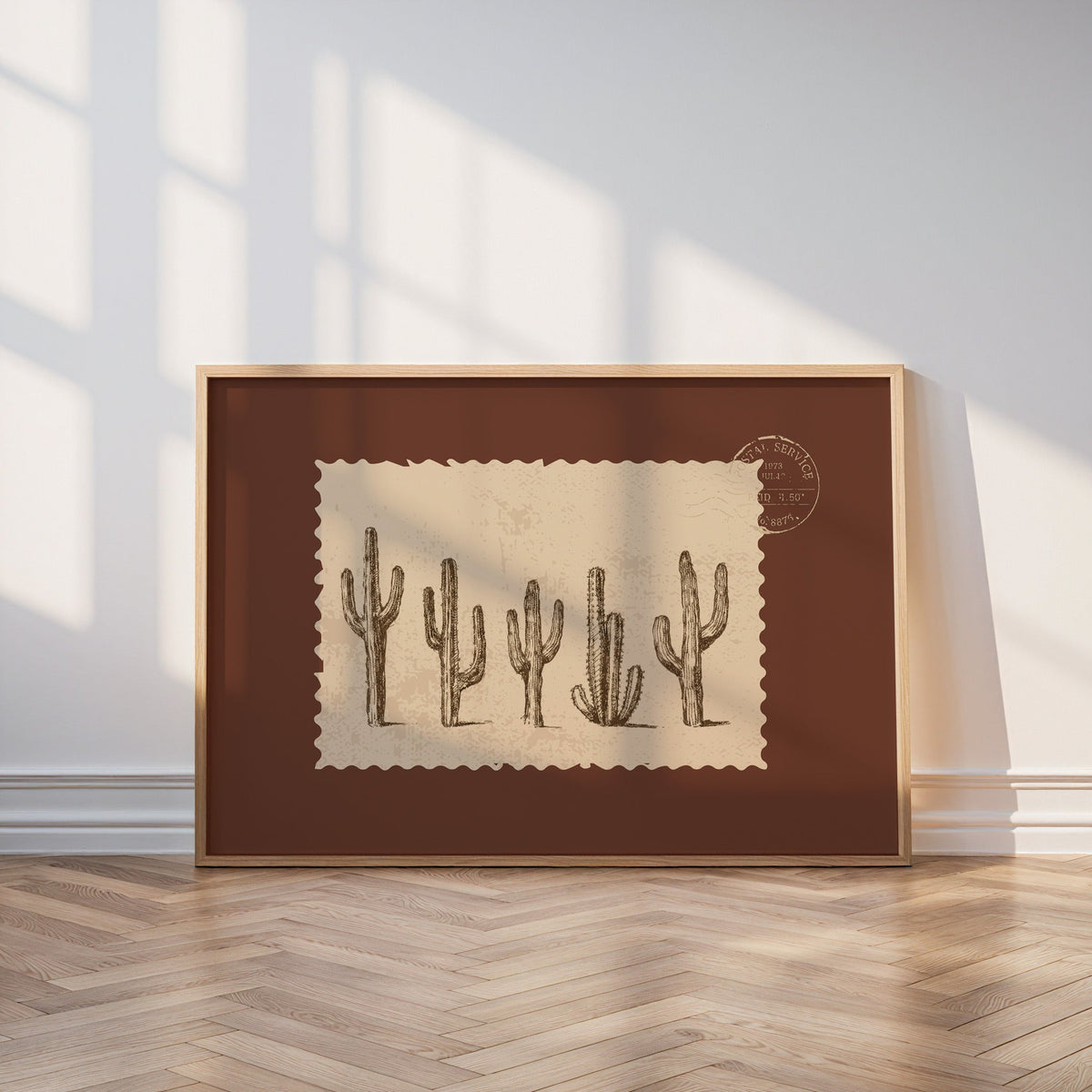 Five cacti print in an oak frame leaning on a parquet floor in window light