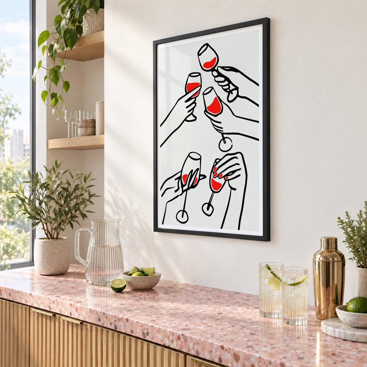 Five hands red wine toast line print in a black frame above a pink terrazzo cocktail counter with limes, seen at an angle