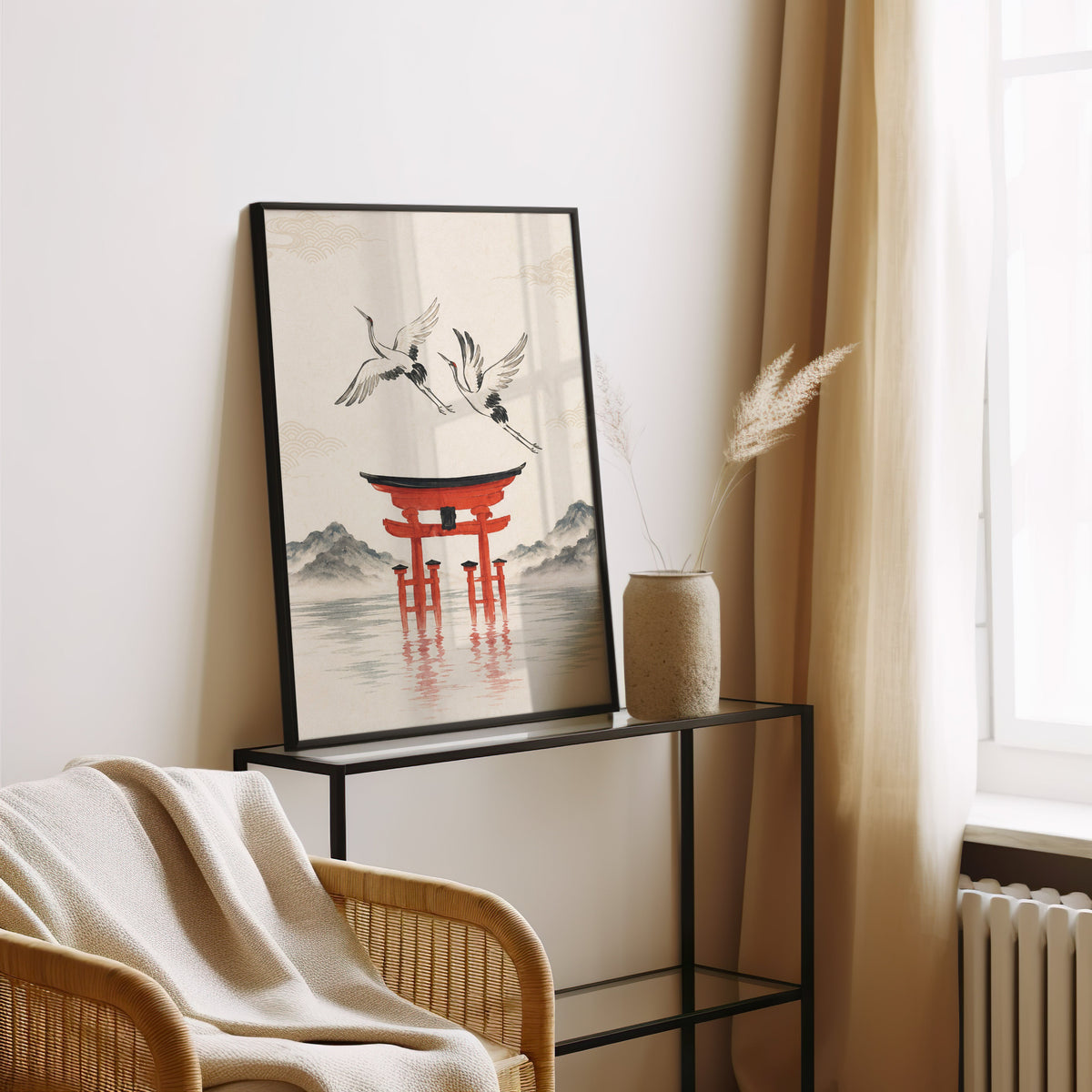 red torii gate with cranes print in a black frame leaning on a glass console beside pampas grass