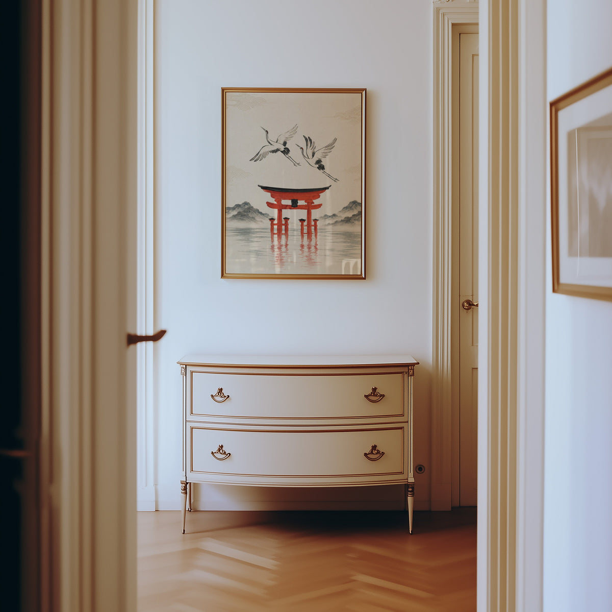 red torii gate with cranes print shown in a gold frame in a hallway above a cream dresser