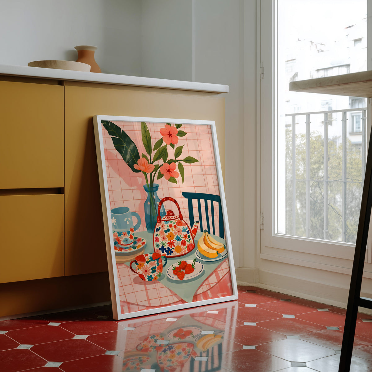 Floral teapot print in a white frame against yellow cabinets on a red tiled floor