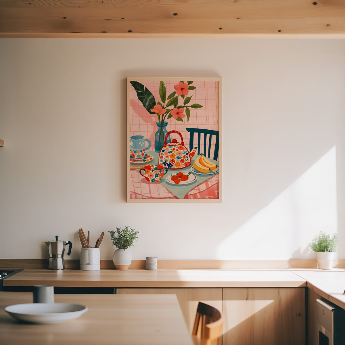 Floral teapot print in an oak frame above a wood counter with a moka pot and herbs
