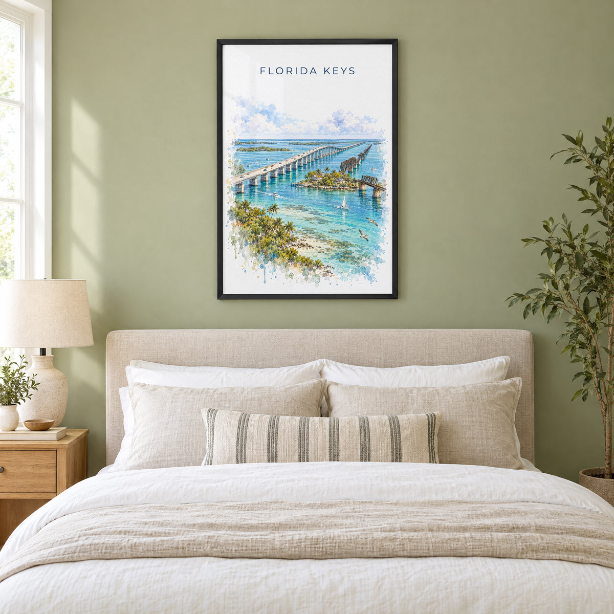 Florida Keys watercolor print in a black frame above an upholstered headboard in a sage green bedroom