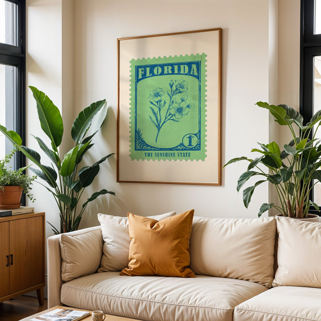 Florida state flower print framed above a cream sofa with an ochre cushion and large plants either side