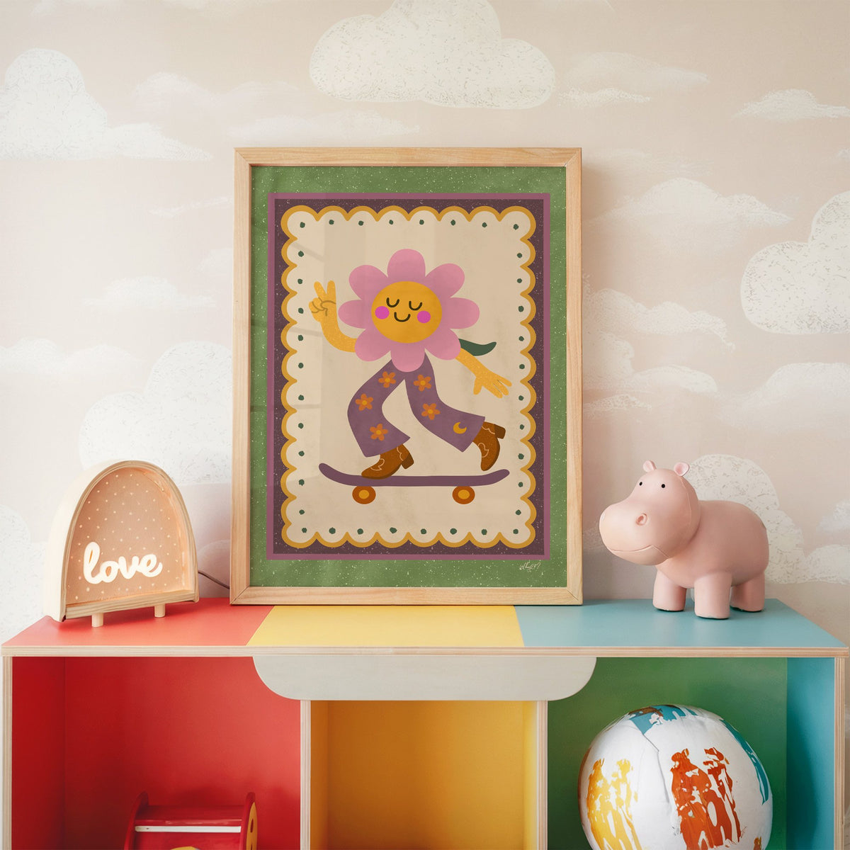 Groovy flower on skateboard nursery print in an oak frame on a rainbow toy shelf against cloud wallpaper
