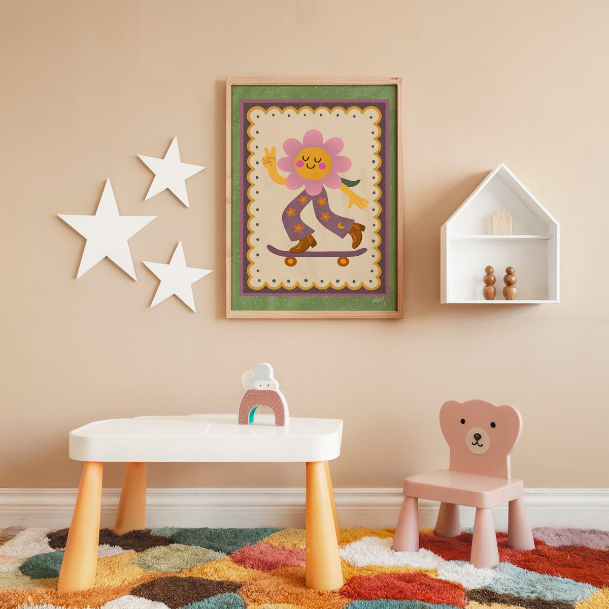 Groovy flower on skateboard nursery print in an oak frame on a peach wall above a kids table with wall stars