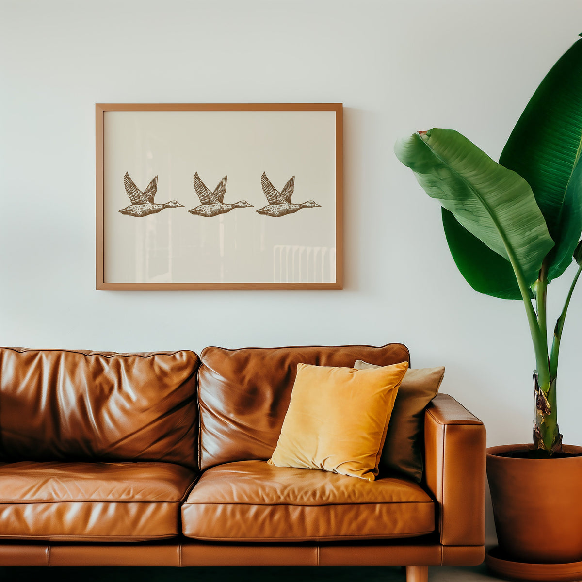Flying ducks trio cream print in an oak frame above a cognac leather sofa