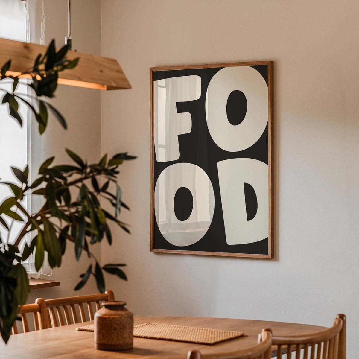 Bold food typography print in a walnut frame above a dining table beside an olive tree