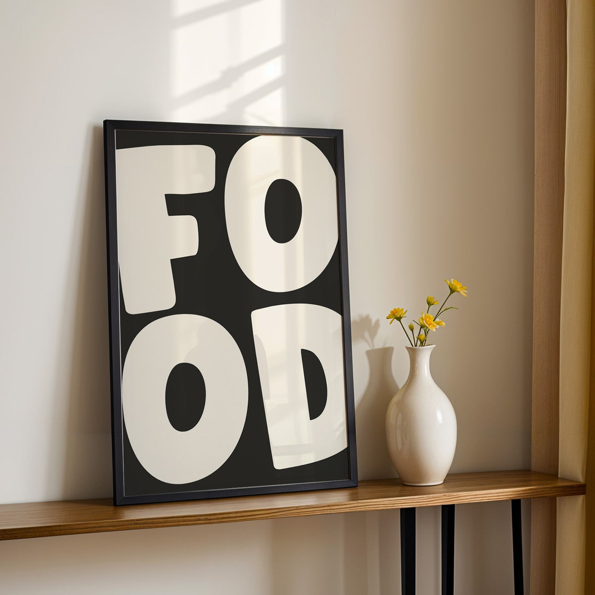 Bold food typography print in a black frame on a console table with yellow daisies