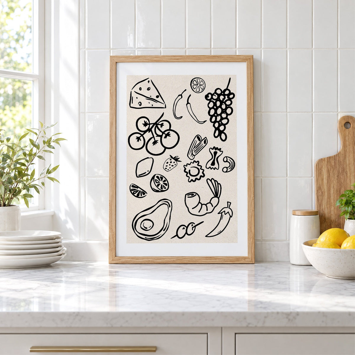Black line food doodle pattern print in an oak frame leaning on a marble counter by white tiles and lemons