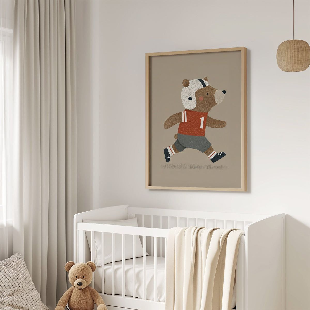 Football bear number one nursery print in an oak frame above a white crib with a teddy bear