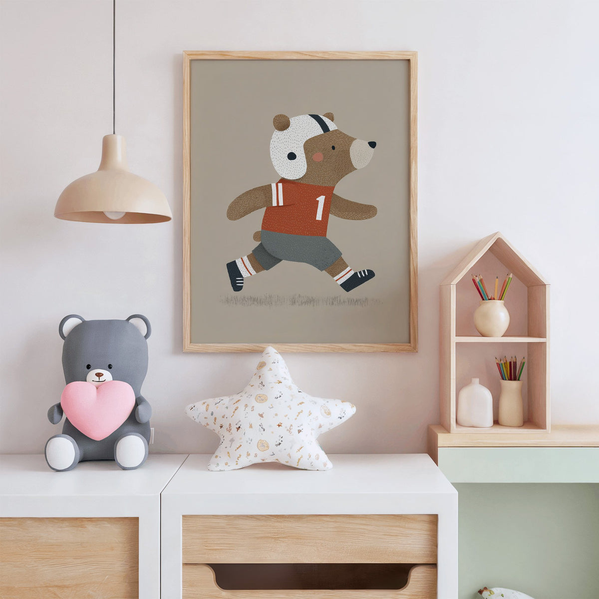 Football bear number one nursery print in an oak frame above a white dresser with a star pillow and house shelf