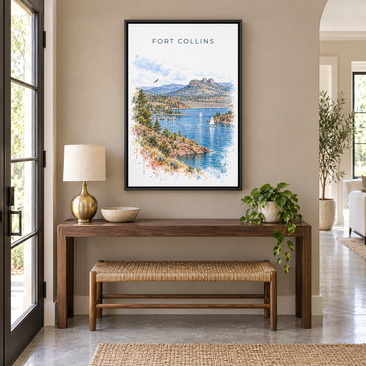 Fort Collins watercolor print as a black floater canvas above a walnut console and woven bench in an entryway
