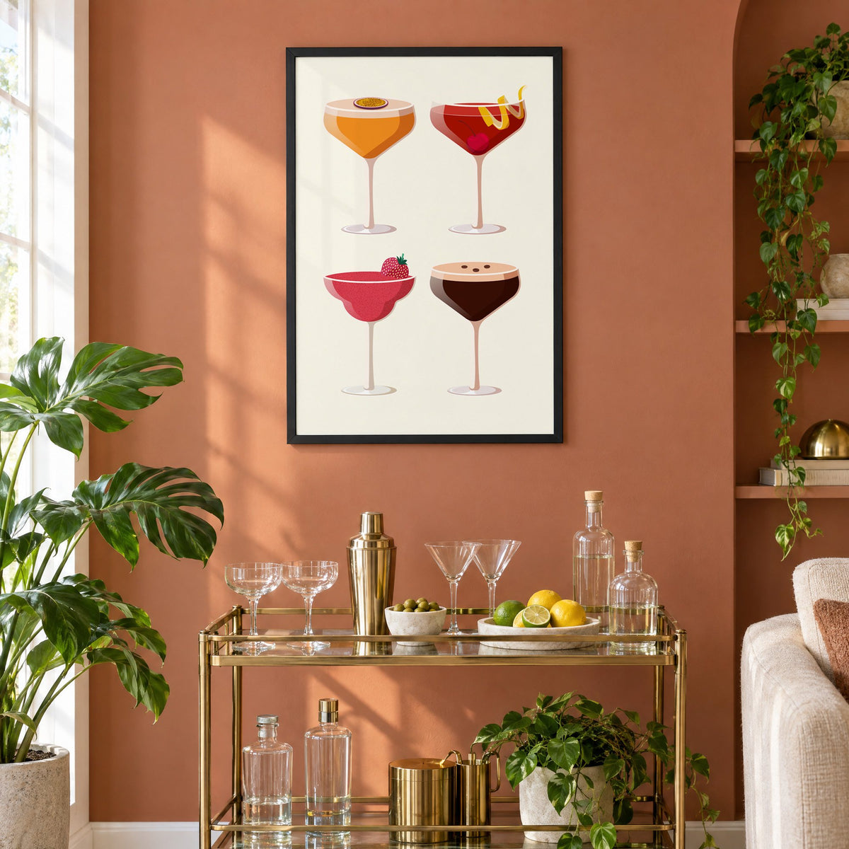 Four coupe cocktails two-by-two grid print in a black frame on a terracotta wall above a brass bar cart with coupes and citrus