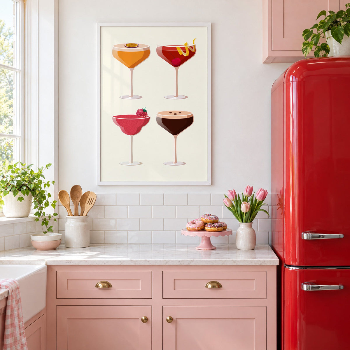 Four coupe cocktails two-by-two grid print in a white frame above pink cabinets beside a red retro fridge