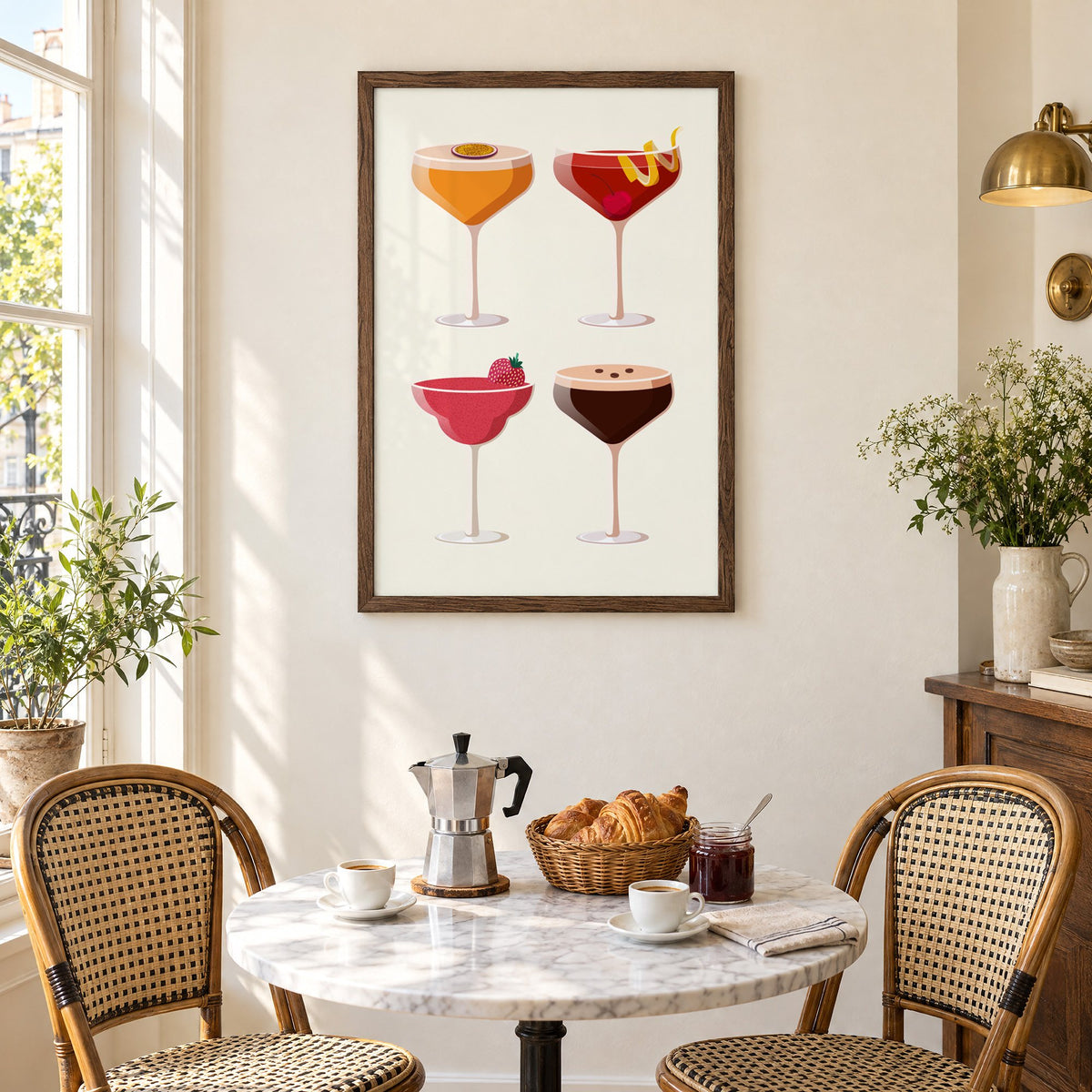 Four coupe cocktails two-by-two grid print in a walnut frame above a marble bistro table with croissants and rattan chairs