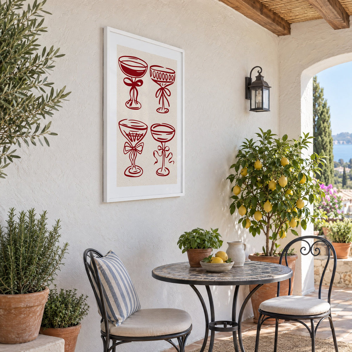 Four red coupe glasses with bows print in a white frame on a sunny patio wall beside a potted lemon tree
