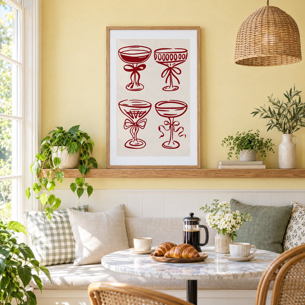 Four red coupe glasses with bows print in an oak frame on a picture ledge above a sunny breakfast nook