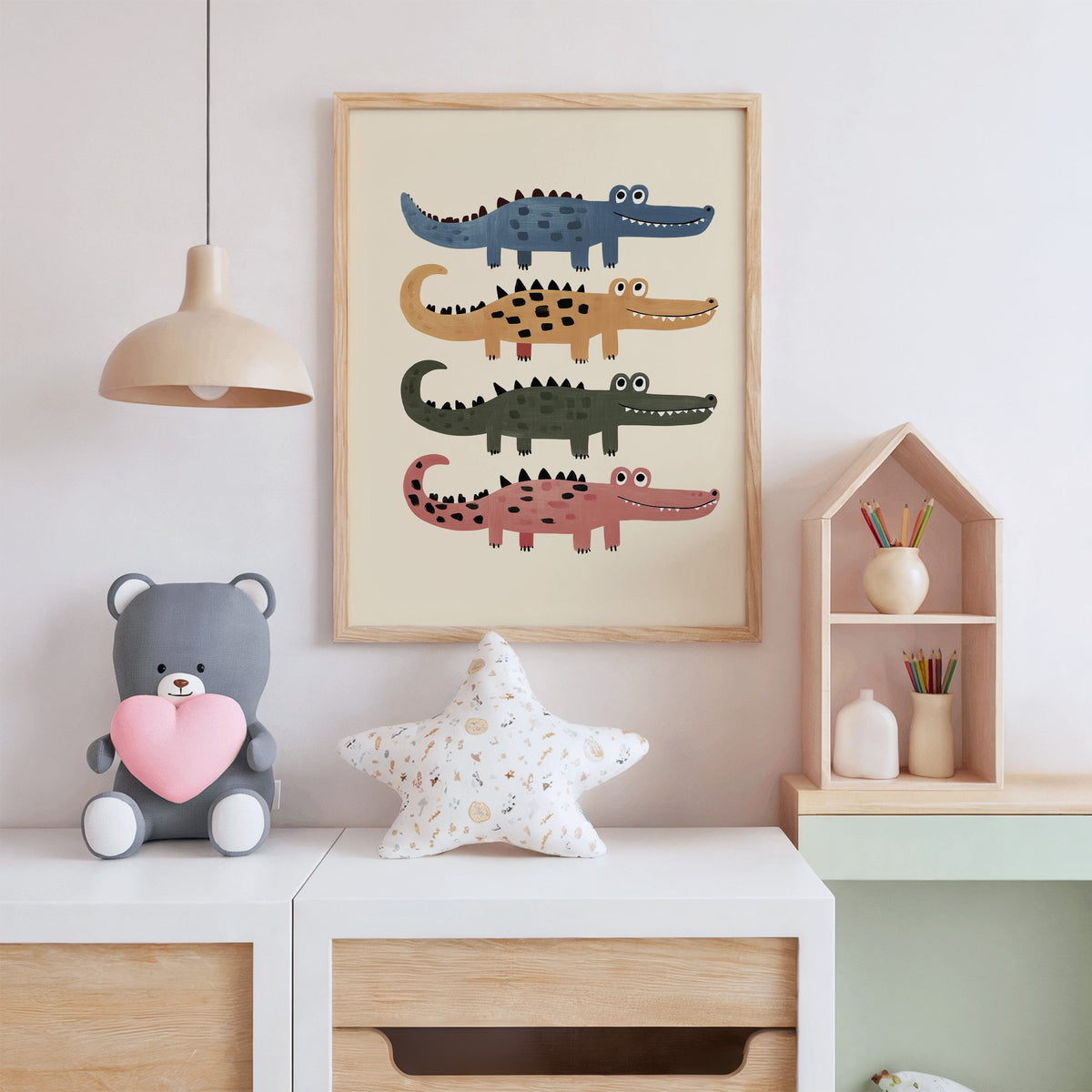 Four stacked crocodiles nursery print in an oak frame above a white dresser with a star pillow and house shelf