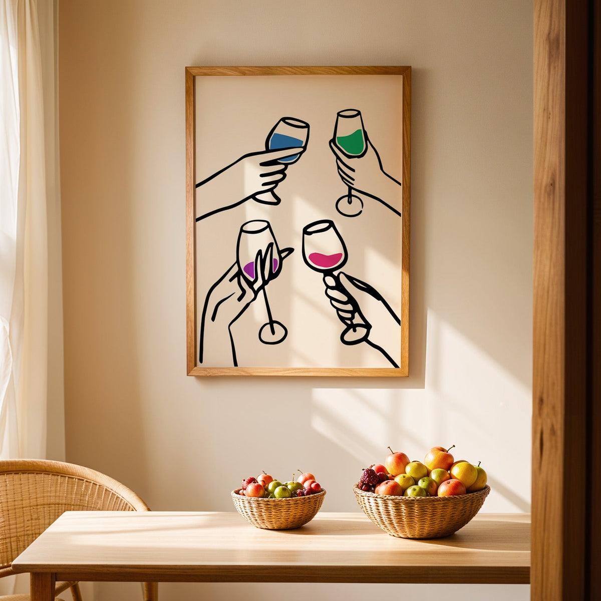 Four hands cheers colour pour print in an oak frame above a light wood dining table with baskets of fruit