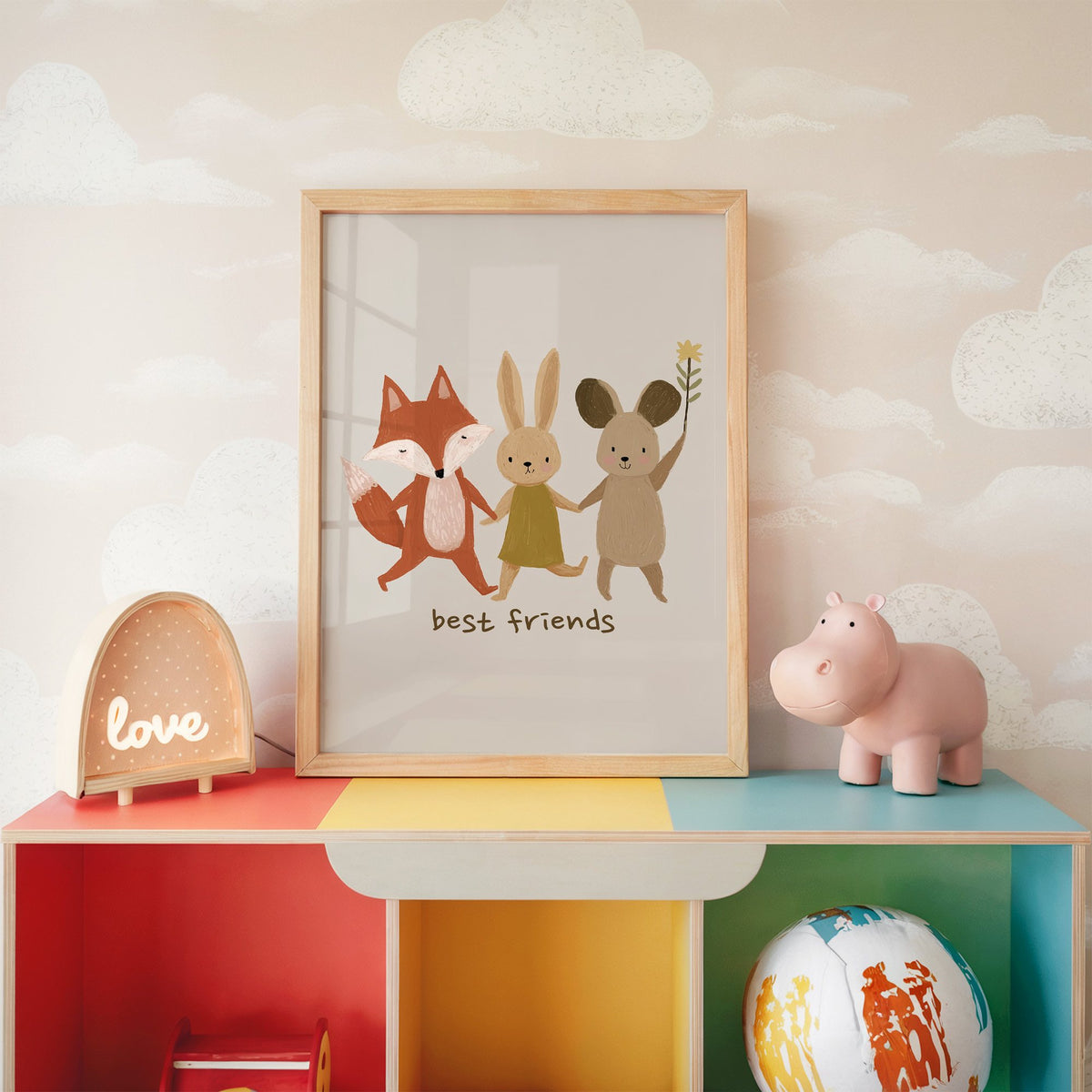 Fox bunny mouse best friends nursery print in an oak frame on a rainbow toy shelf against cloud wallpaper