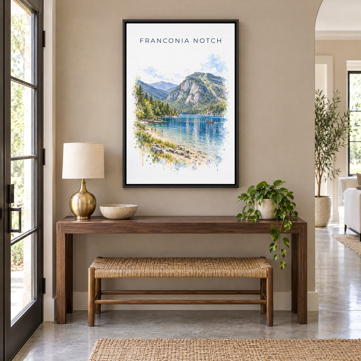 Franconia Notch watercolor print as a black floater canvas above a walnut console and woven bench in an entryway