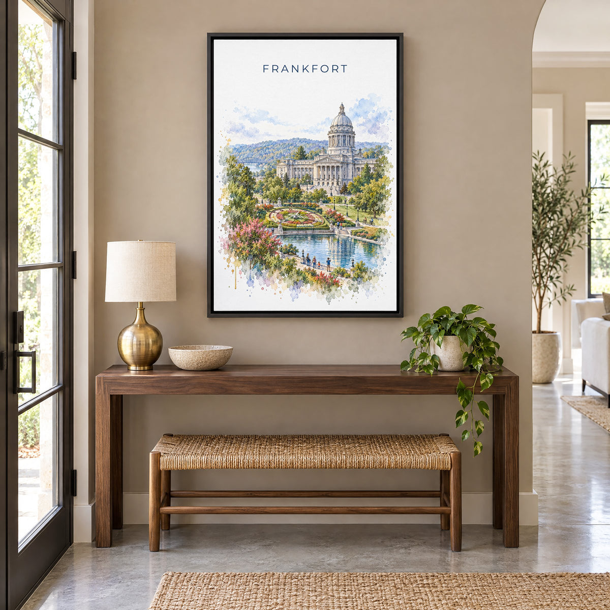 Frankfort, Kentucky watercolor print as a black floater canvas above a walnut console and woven bench in an entryway