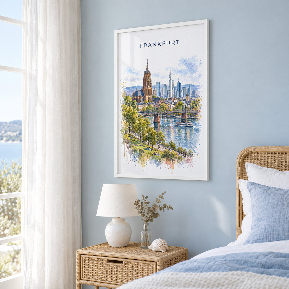 Frankfurt watercolor print in a white frame on a pale blue wall beside a rattan bed in a coastal bedroom