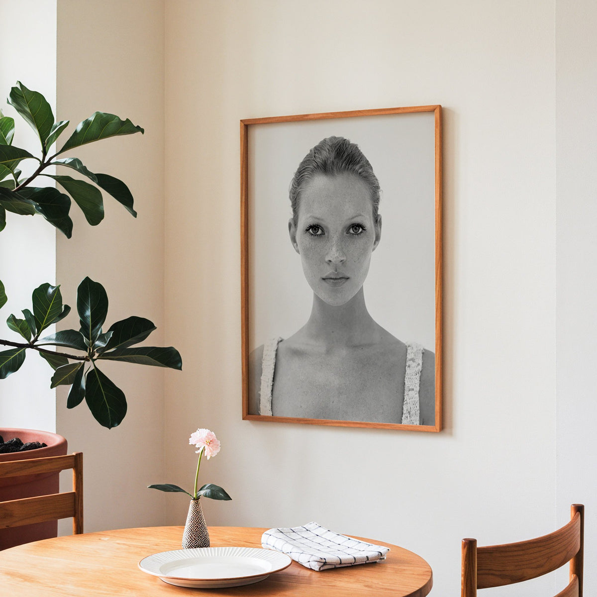 Freckled woman in lace tank top portrait print in a teak frame above a round wooden dining table