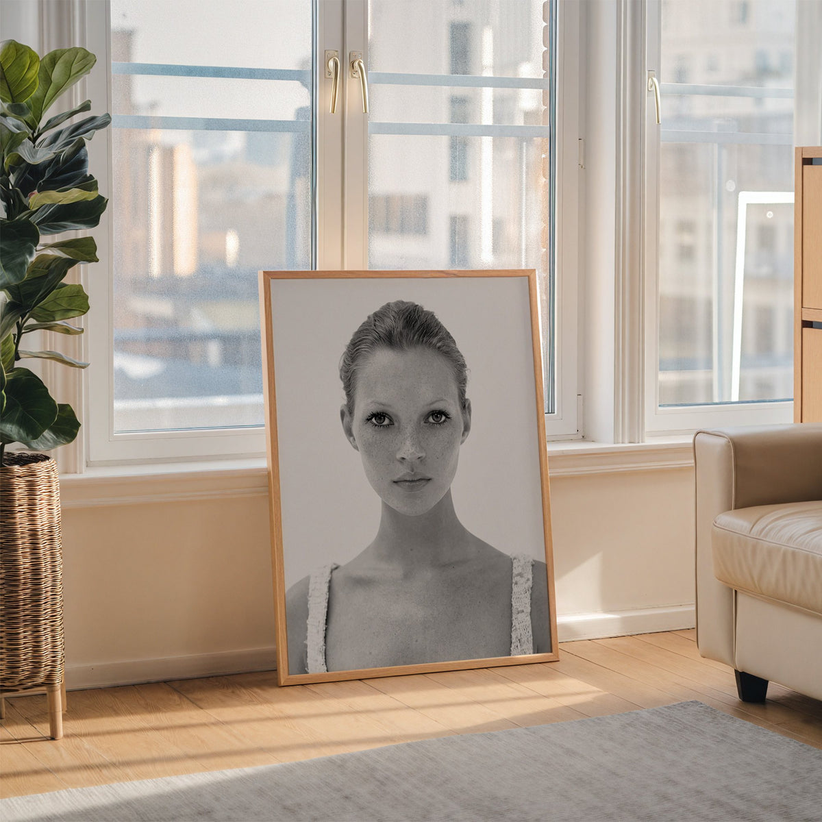 Freckled woman in lace tank top portrait print in an oak frame leaning on the floor beside a fiddle leaf fig