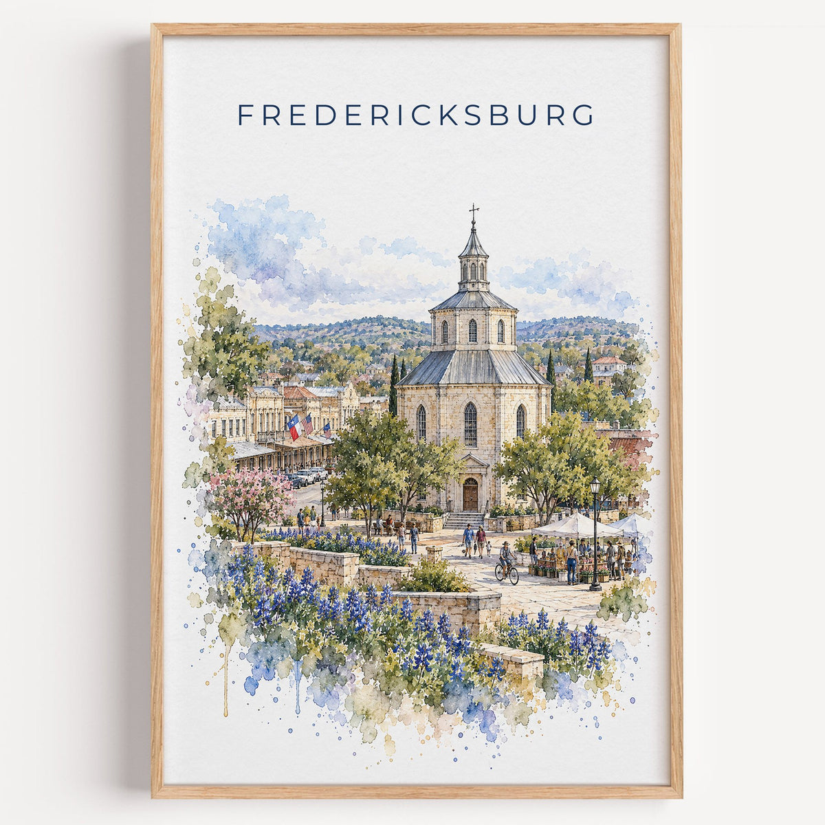 Fredericksburg, Texas watercolor print in a light oak frame on a plain white wall