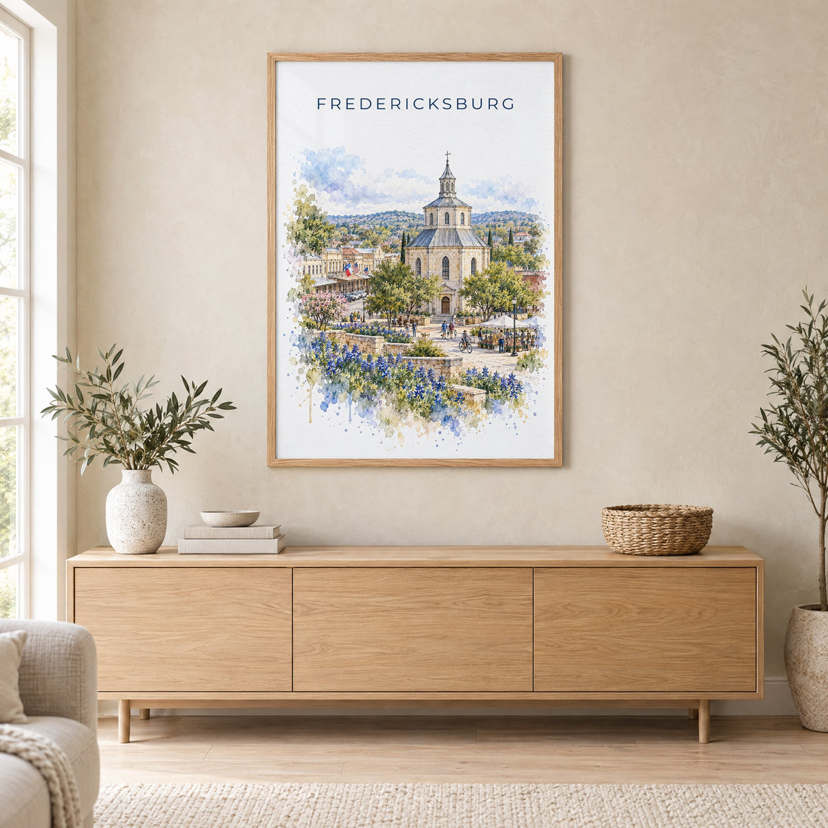 Fredericksburg, Texas watercolor print in an oak frame above a light wood sideboard in a Scandinavian living room