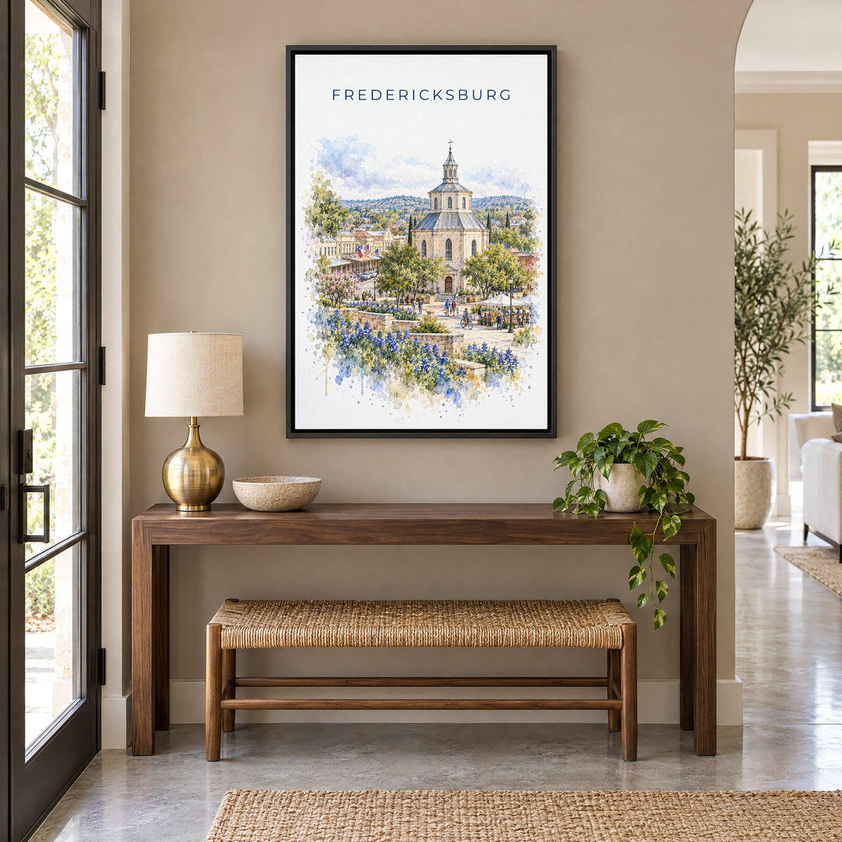 Fredericksburg, Texas watercolor print as a black floater canvas above a walnut console and woven bench in an entryway