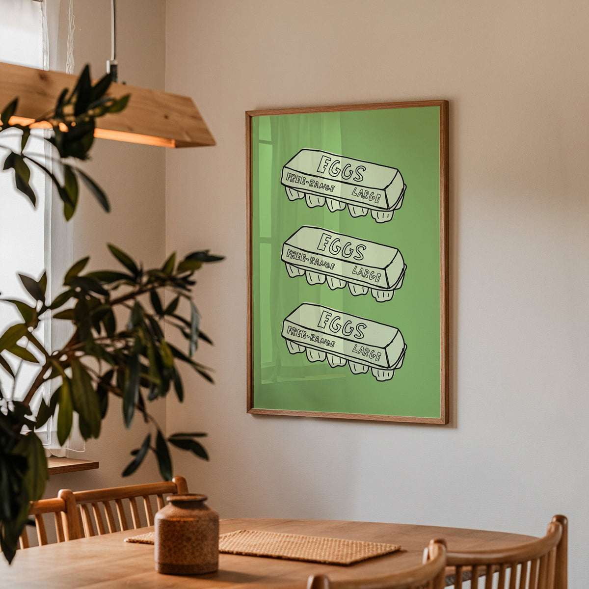 Free range eggs carton print in a walnut frame above a dining table beside an olive tree