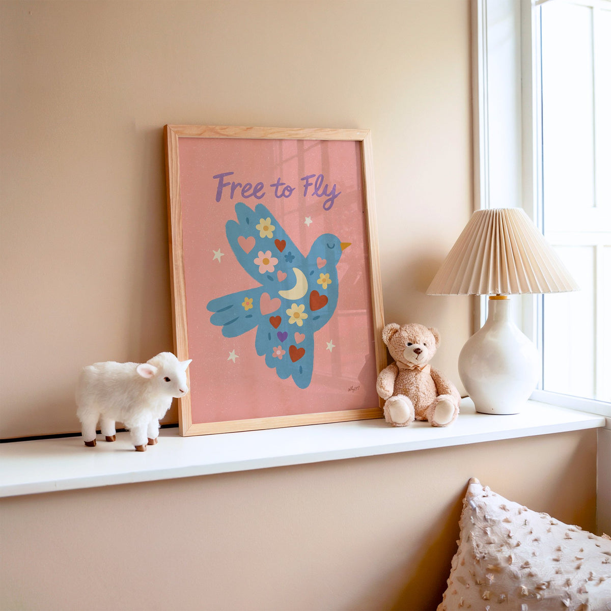 Folk blue bird free to fly nursery print in an oak frame on a window ledge with a toy lamb and teddy