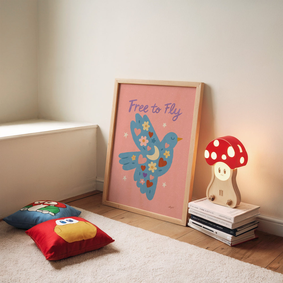 Folk blue bird free to fly nursery print in an oak frame leaning on a rug beside a mushroom lamp and floor cushions