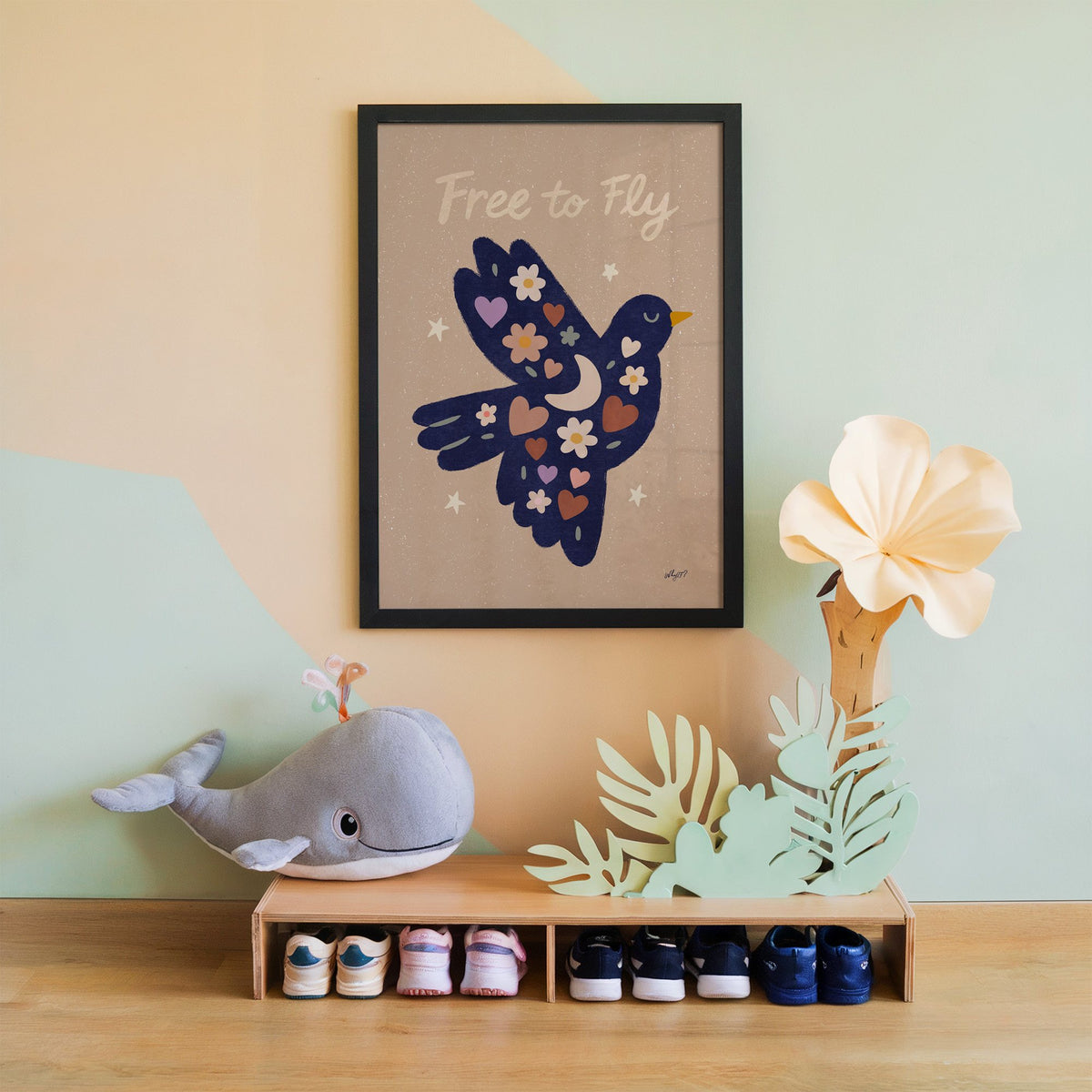Navy folk bird free to fly nursery print in a black frame on a mint and peach wall above a whale plush