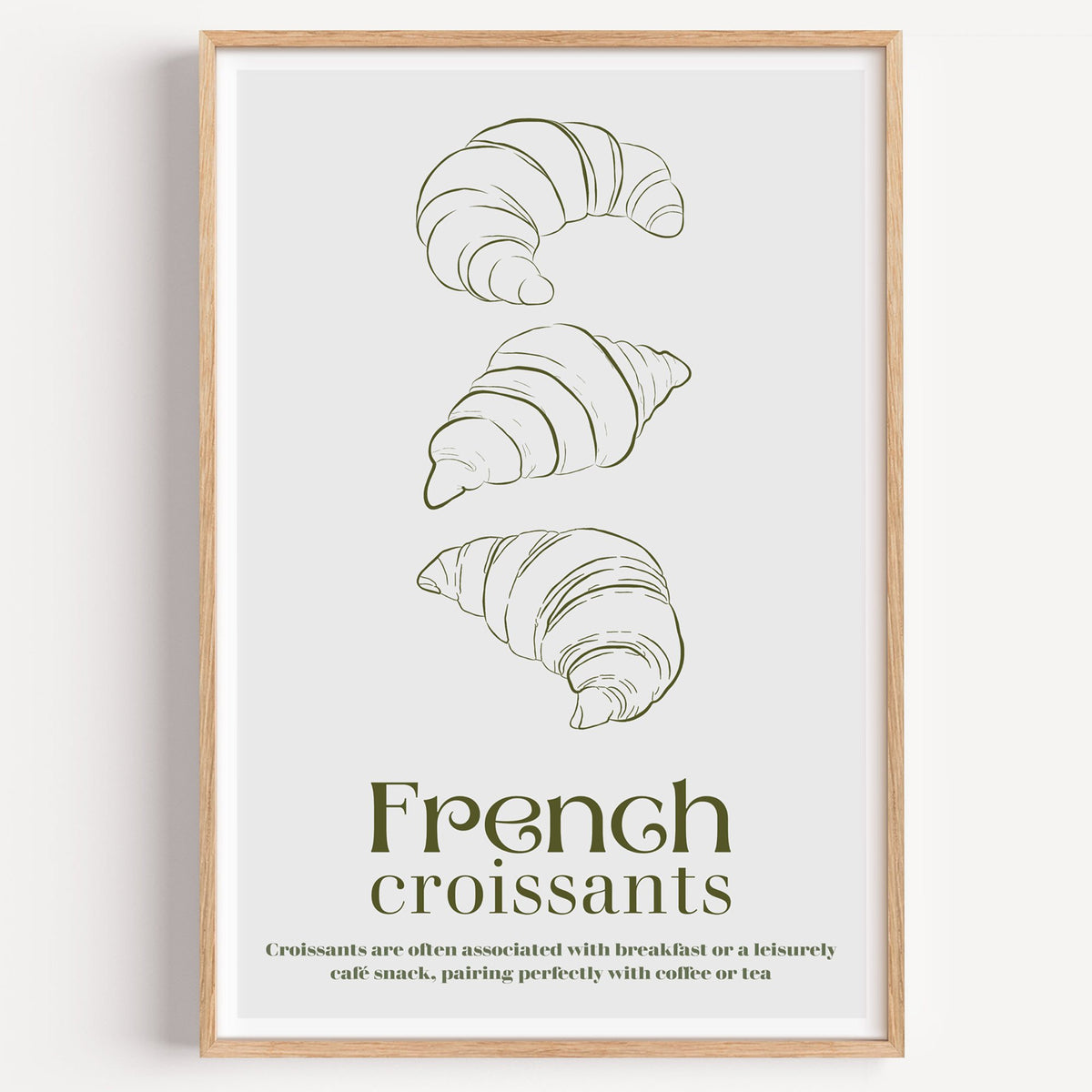 French croissants olive line print in a light oak frame on a plain white wall