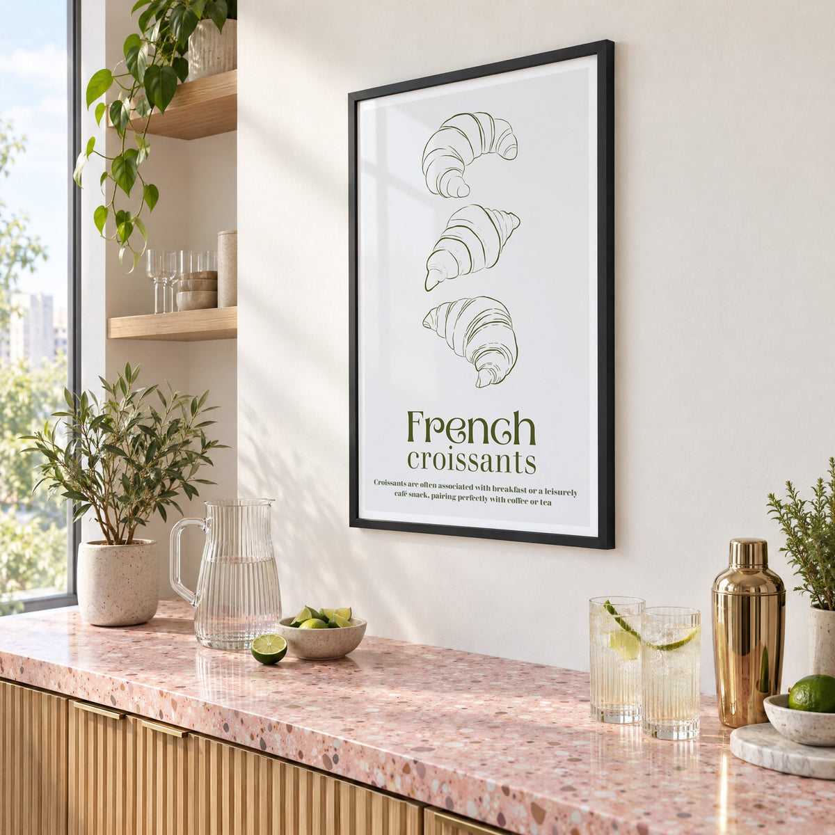 French croissants olive line print in a black frame above a pink terrazzo cocktail counter with limes, seen at an angle
