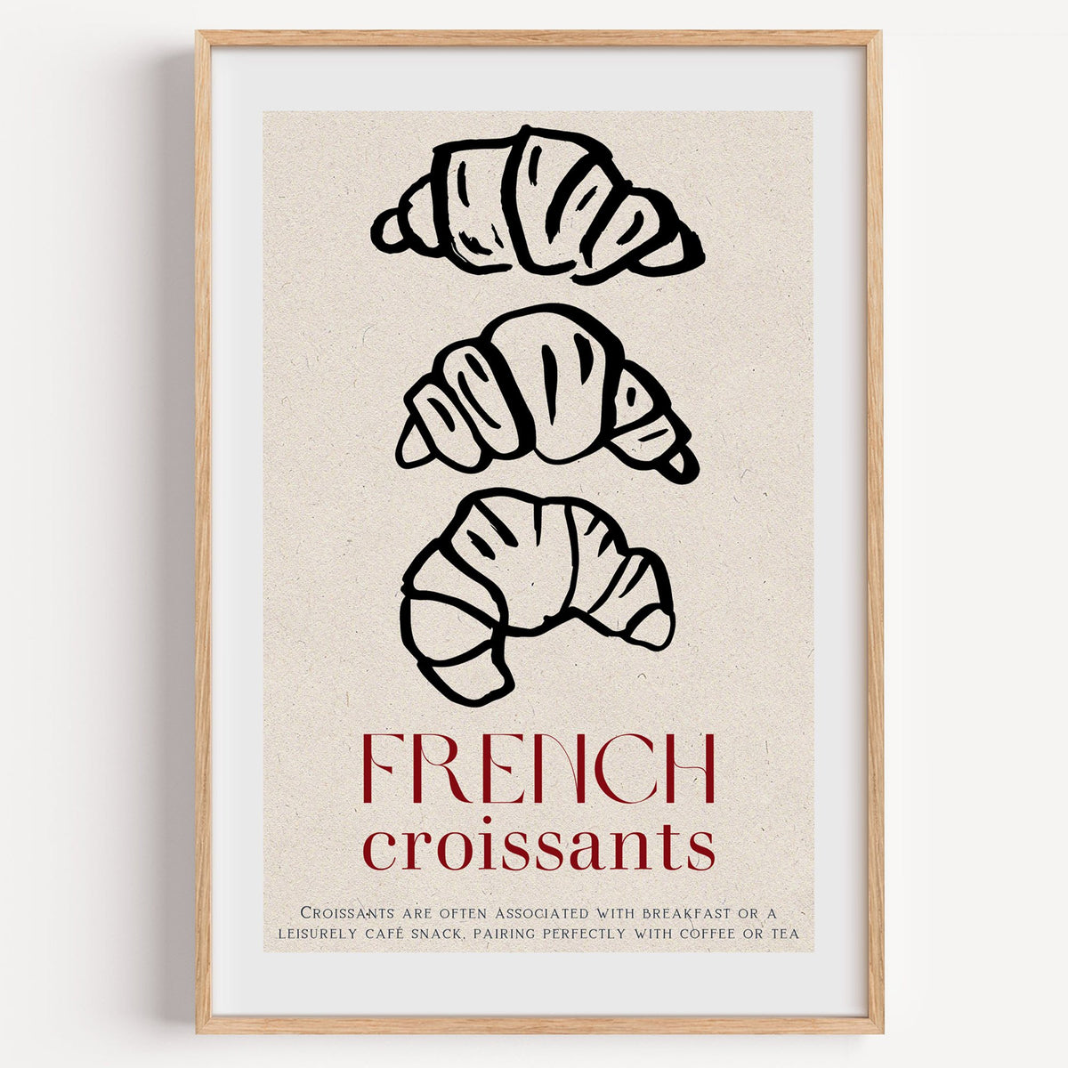 FRENCH croissants black line-art print in a light oak frame on a plain white wall