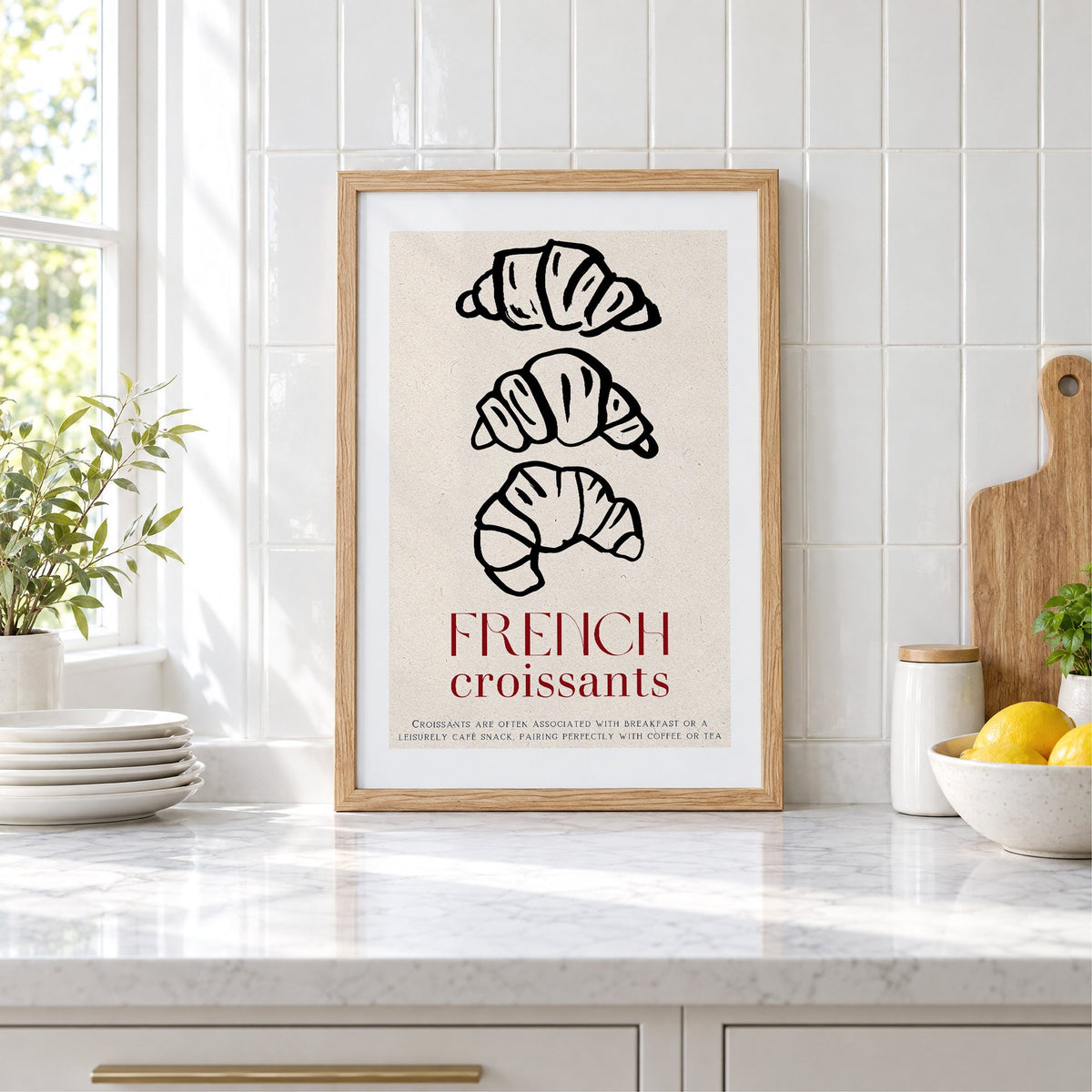 FRENCH croissants black line-art print in an oak frame leaning on a marble counter by white tiles and lemons