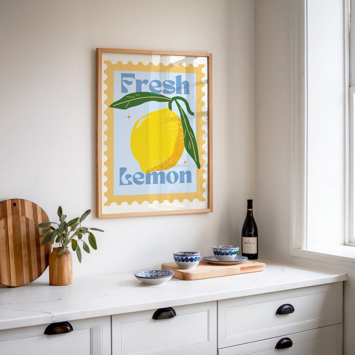 Fresh Lemon stamp print in an oak frame above a white sideboard with a bottle of wine