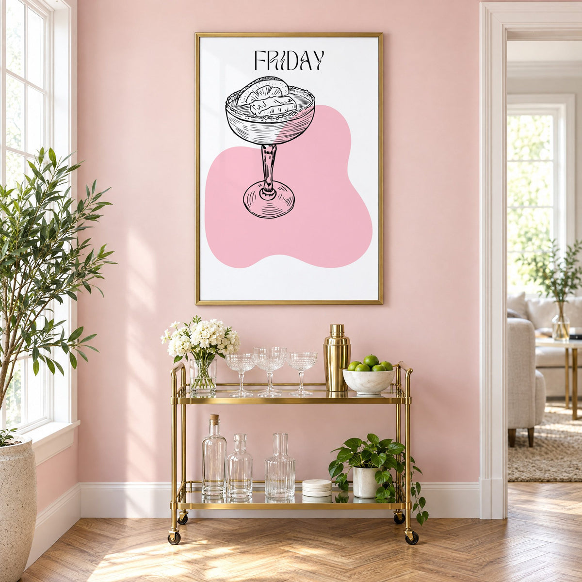 FRIDAY engraved coupe cocktail pink blob print in a brass frame on a blush pink wall above a gold bar cart with glassware