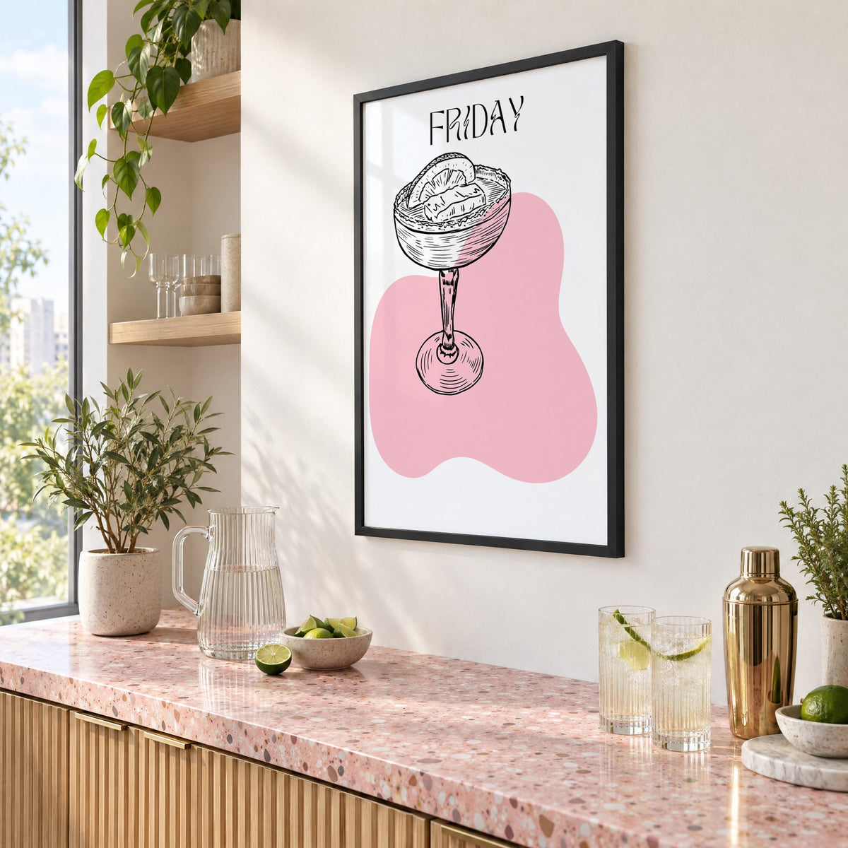 FRIDAY engraved coupe cocktail pink blob print in a black frame above a pink terrazzo cocktail counter with limes, seen at an angle