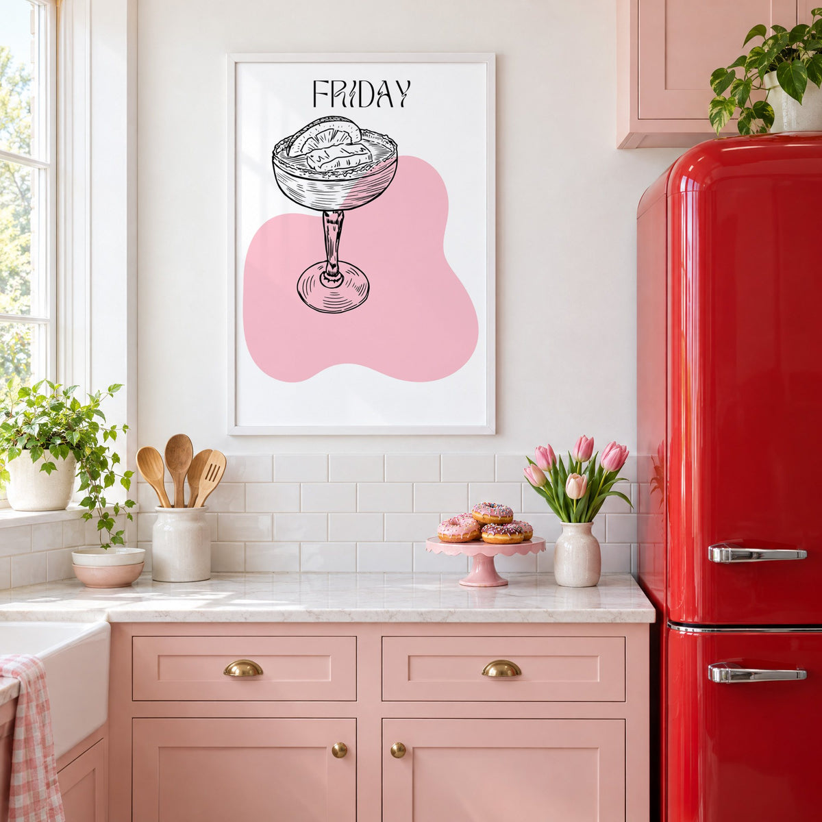 FRIDAY engraved coupe cocktail pink blob print in a white frame above pink cabinets beside a red retro fridge