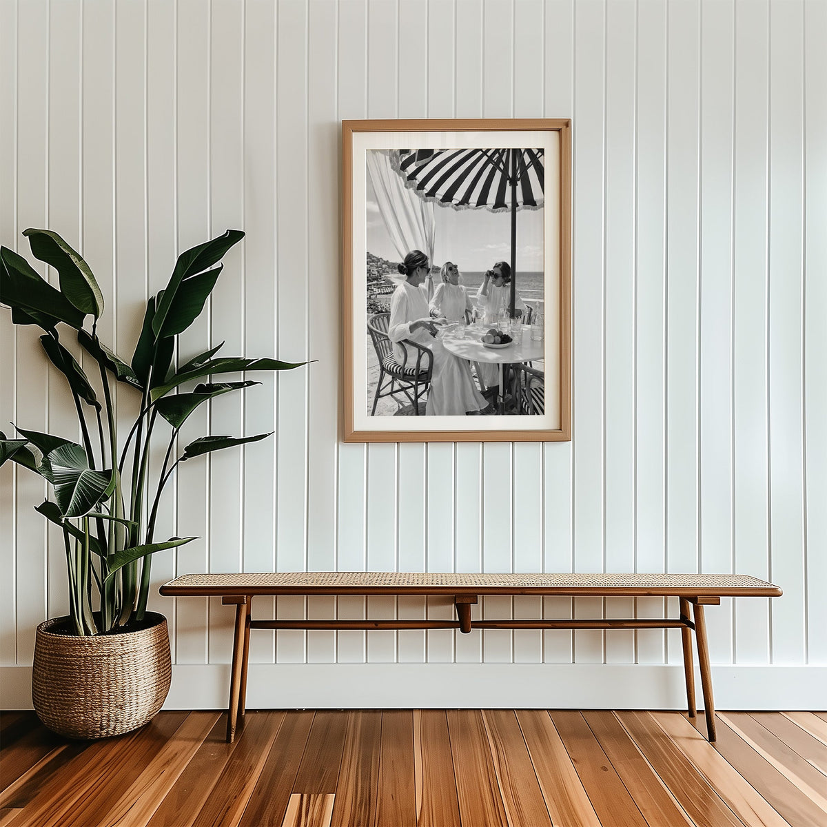 Three friends lunching under a striped umbrella print in a wood frame with a white mat above a cane bench