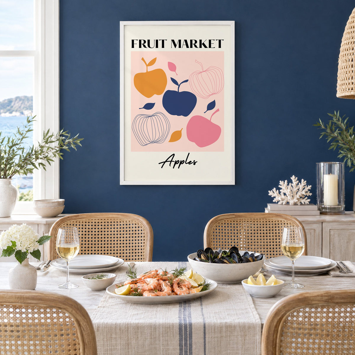 FRUIT MARKET Apples cut-paper print in a white frame on a navy wall above a dining table set with shrimp and mussels