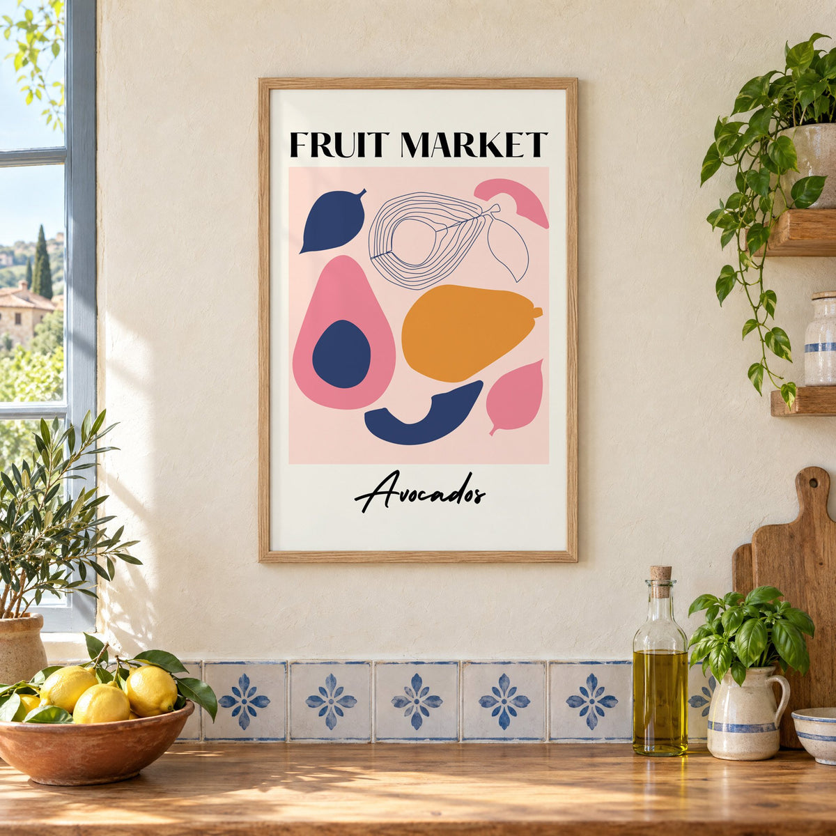 FRUIT MARKET Avocados cut-paper print in an oak frame on a cream plaster wall above a worktop with a bowl of lemons and blue-and-white tiles